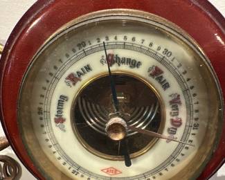 Ship's Wheel Wall Barometer — Ship's Wheel Wall Barometer with a brass and wood case styled as a ship's wheel; the dial reads weather indications including "Stormy," "Rain," "Change," "Fair," and "Very Dry." The central visible aneroid mechanism and coiled spring are intact and the piece shows patina and light surface wear consistent with age, visible on the brass and wood rim. A decorative maritime piece suitable for wall display or nautical-themed decor; appears complete with mounting hardware visible in photos. Condition is good with expected tarnish and minor scuffs but no obvious breaks.