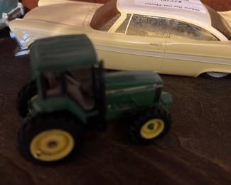 Green Toy Tractor Diecast — Small green diecast toy tractor with yellow wheels shown with other model cars. Solid metal construction with painted finish; some paint wear and light scuffs visible on body and wheels consistent with play use. Compact tabletop model suitable for display or children's play; no visible maker's mark in photos. Sold as pictured.