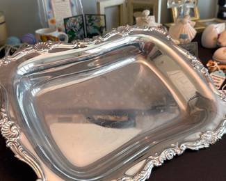 Ornate Silver-Plate Serving Dish — Large ornate silver‑plate serving bowl with a deep rectangular basin and heavily embossed rococo border. The decorative molded rim and corners show scroll and shell motifs; finish is bright with light surface scratches and scattered small dings consistent with normal use. Heavy, substantial feel suitable for buffet or centerpiece service; no maker's marks legible in the photos. Good usable condition cosmetically consistent with vintage silver‑plated hollowware.