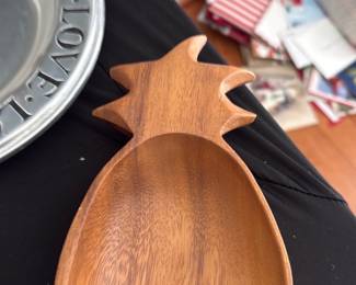 Carved Wood Pineapple Dish — Hand-carved pineapple-shaped wooden dish or small tray with a warm medium-brown finish. Solid carved form shows natural wood grain and is ideal for keys, jewelry, or small serving; there is residue from an old sticker on the back and minor surface wear consistent with light use. No maker's marks visible in photos; lightweight, decorative and functional for tabletop or entryway use. Measures small enough for countertop display or catchall use.