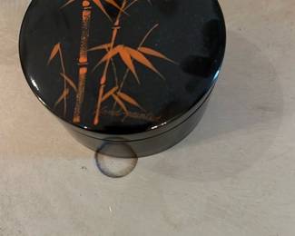 Lacquer Ware Coasters — Small black lacquered trinket/tea caddy decorated with gilded bamboo motif, marked on the base with a label reading "Alcohol & Stamproot Lacquer Ware" and "Made in Japan." The round two-piece box has a glossy finish with hand-painted gold bamboo and appears intact with light surface wear consistent with age. Ideal for decorative storage or tabletop display; lid fits snugly and there are no visible chips or cracks in the photos.