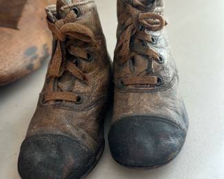 Child's Leather Boots — A pair of antique child's leather lace-up boots with rounded toes and stitched toe caps. The leather shows heavy age patina, scuffs, surface wear and creasing consistent with long use; laces are present but worn. Suitable as a decorative vintage display piece or for a collector of children's footwear; both boots appear intact with no obvious sole separation visible in photos. Sold as shown.