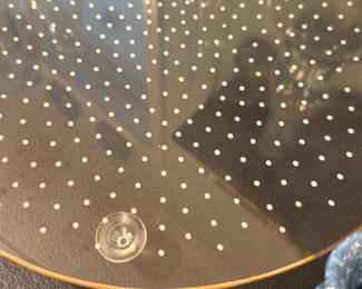 Cake stand — Clear glass cake stand with small white polka dot pattern and a thin gold rim. Three small suction-style feet attach to the underside for stability; top surface is flat and suitable for cakes or desserts. Light surface wear visible in photos but no major chips or cracks noted. Measures approximately tabletop size and is a decorative serving piece.