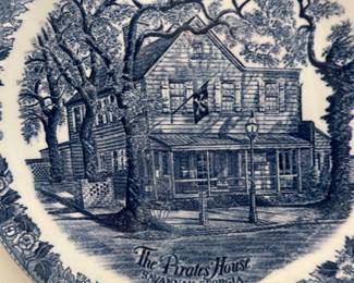 The Pirates House Blue Collector Plate — Decorative collector plate featuring a detailed blue transferware image of The Pirates' House, Savannah, Georgia. Porcelain/ceramic construction with floral border and central historic building scene; likely intended as a souvenir or wall display in the living room. Plate measures approximately 10 inches diameter and is lightweight for easy hanging; ideal for wall grouping or coastal/southern decor. Good condition with no visible cracks or chips in the photo; minor surface wear or crazing possible from age.