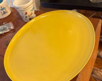Vintage Florence Prolon Platter — Large yellow ceramic oval platter with a glossy glaze and gently upturned rim. Simple, solid-color design suitable for serving or display; photos show light surface wear and a few minor scuffs consistent with normal use. No visible maker's marks in the provided images; sturdy construction and bright color make it a practical serving piece for casual dining or entertaining. Measures approximately as listed and sold as shown.
