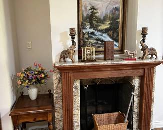 More framed art above the fireplace is near the elephant candle holders, the small table and other decorative items.