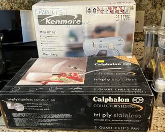 This close-up photo shows a 3 quart stainless steel chef's pan from Calphalon, and a stand mixer from Kenmore.
