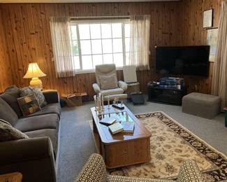 This overview look at the living room shows not only the deep blue sofa, but two armchairs, a coffee table, an entertainment table with television, and the area rug.