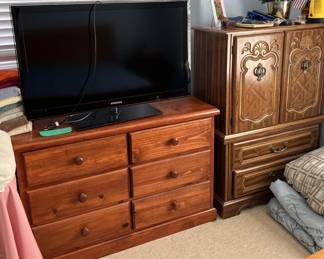 Here we have a television monitor, a six-drawer dresser, and a short armoire.