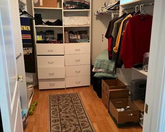 This walk-in closet holds more clothing and a runner rug.