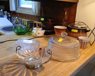 Kitchen Counter: Cake Plate, Slow Cooker, Enamel Kettle & Glassware Tags: glass cake plate and dome, vintage slow cooker, enamel teakettle, Pyrex fruit design bowl, oil lamp, green glass bowl, footed glass punch bowl, kitchen collectibles A nice mix of vintage kitchen finds: a footed glass cake stand with dome cover ($12), a copper-tone 1970s slow cooker with warming tray set ($20), and a cheerful floral enamel teakettle. Also featured — a Pyrex bowl with fruit design, a green glass footed bowl, an antique oil lamp, and elegant scalloped glass bowls with silver handles, great for entertaining or displaying.