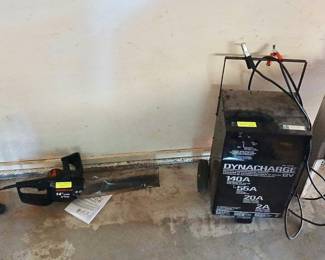 Dynacharge 12V Battery Charger/Engine Starter & Electric Chainsaw Tags: Dynacharge battery charger, 12V engine starter, electric chainsaw, Remington chainsaw, garage power equipment, automotive tools A Dynacharge 12V battery charger/engine starter (140A/55A/20A/2A settings) on wheels is a practical find for any garage or workshop. Alongside it, a Remington 14” electric chainsaw is ready for light trimming and limb work — great functional tools for home or yard maintenance.