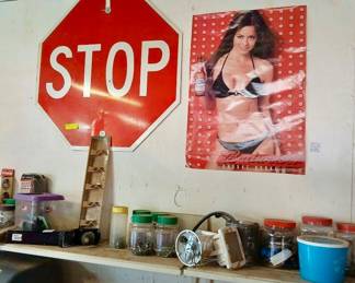 Vintage Stop Sign & Budweiser Advertising Poster Tags: vintage stop sign, red road sign, Budweiser advertising poster, garage wall decor, storage shelf with glass jars, man cave collectibles A genuine red STOP sign makes for a bold, retro garage or man cave piece, paired with a vintage Budweiser advertising poster. Below, a shelf holds an assortment of glass jars with hardware, a small jack, and miscellaneous storage containers — practical extras for any garage.