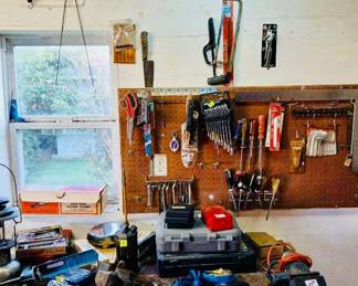 Pegboard Tools & Fully Stocked Workbench Tags: vintage metal name sign, pegboard tool organizer, wrench set, screwdrivers, hacksaw, tool box, vise, garage workbench tools A well-organized pegboard displays a full set of wrenches, screwdrivers, a hacksaw, and scissors, hung neatly under a vintage “KENNY” metal name sign — a nice personal touch. The workbench below holds a rolling tool box, socket sets, a bench vise, and an assortment of hand tools, ready to be put right back to work in someone else’s garage.