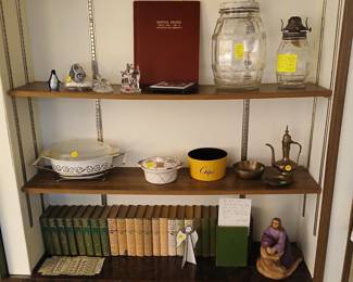 Local History Book, Antique Glass Jars & Year Book Set Tags: Spearville WWI WWII service record, antique glass pickle jar, oil lamp, Pyrex casserole dish, brass Turkish coffee pot, vintage year books, collectible figurines, primitive religious statue A standout piece of local history: a hardbound “Service Record, World War I and II — Spearville and Community” book, priced at $20. Nearby, a large antique glass pickle jar and an oil lamp add vintage charm. Below, a run of vintage Pyrex-style casserole dishes, a brass Turkish-style coffee pot, and a complete 26-volume set of New Standard Year Books (1932–1958) make this a rich shelf for collectors of local and general Americana.