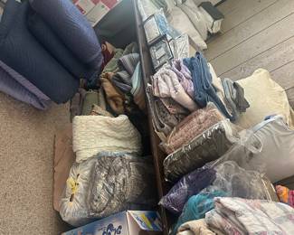 A bedroom full of linens. Multiple king sized sheet sets & comforters, pillows, new in the packaging.