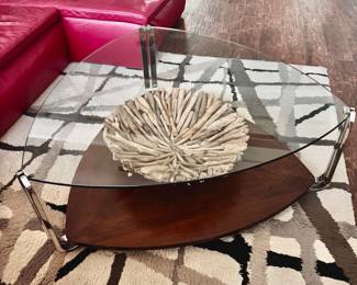 Two-tiered coffee table features a rounded triangular clear glass top, three chrome metal legs and matching dark wood lower base.