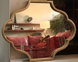 Decorative wall mirror features a classic quatrefoil silhouette boardered by a simple gold-tone frame.