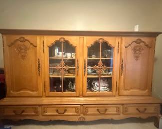 This large European-style antique oak sideboard with display cabinets, carved details, and glass panels is an exceptional piece that offers the perfect blend of Old World charm and everyday practicality. Constructed from oak, it will elevate any space in your home.