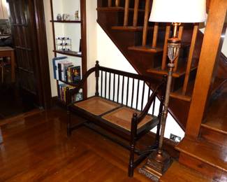 Vintage mahogany spindle back settee with cane seats, floor lamp, books
