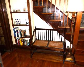 Vintage mahogany spindle back settee with cane seats, floor lamp, books
