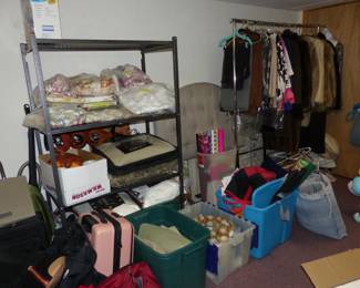 Basement with lots of assorted things including tablecloths, clothing & furs