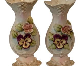 419 - Pair of Ceramic Vases w/ Applied Floral Pansies (Description): Pair of ceramic vases featuring applied floral decoration with pansies and roses. Each vase has a bulbous body with a ruffled rim and ornate ruffled base, decorated with pink and purple pansies and green leaves. The white ground is accented with gold gilt detailing. Measures 10 1/2" x 4".