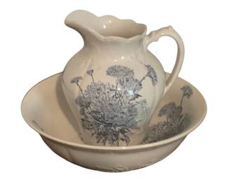 499 - Ceramic Pitcher & Bowl Set w/ Blue Floral (Description): White ceramic pitcher and bowl wash basin set featuring a blue transferware-style floral design depicting chrysanthemums. The pitcher has a scalloped rim and decorative handle. Measures 12 inches by 5 inches.