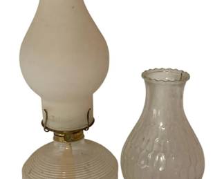 468 - Vtg Clear Glass Oil Lamp w/ Extra Globe 15.5" (Description): Vintage oil lamp with extra globe measuring 15.5 inches tall. The lamp features a clear pressed glass base with horizontal ribbing and geometric pattern details, topped with a brass collar and burner assembly. The lamp is fitted with a frosted white glass chimney. An additional clear glass globe with a quilted diamond pattern and scalloped rim is included.