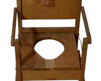 493 - Vtg Wood Child's Potty Chair 17.5"x13"x11.5" (Description): Vintage wooden child's potty chair featuring a charming bunny decal on the backrest. The chair is constructed of painted wood in a warm tan or mustard color with a simple, sturdy frame design including armrests and a footrest. The seat has a circular opening for practical use. Shows wear consistent with age and use. Measures 17 1/2" x 13" x 11.5".