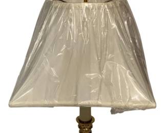 123 - Brass Candlestick Style Table Lamp w/ Shade (Description): Brass candlestick style table lamp featuring a fluted column design with decorative Corinthian-style capital and an ornate square base with classical motifs. Topped with a ring finial and includes a pleated fabric shade in original plastic wrapping. Measures 30 inches tall. Used as is electric/electronic/mechanical item. No guarantee all components, untested.