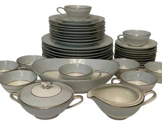 205 - 38pc Noritake "Laureate" China Dinnerware (Description): 38pcs of Noritake "Laureate" pattern china. The set features an elegant pale blue-gray tone with delicate white floral embossing and platinum trim. Pieces include dinner plates, salad plates, bread plates, cups, saucers, a covered sugar bowl, creamer, and serving bowl.