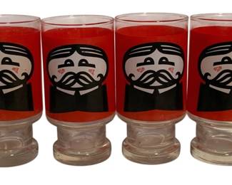 8 - 4 Pringles Promotional Drinking Glasses (Description): Set of four vintage Pringles promotional drinking glasses featuring the iconic mustachioed mascot. Each glass displays the character's face in black and white against a bold red background. The glasses have clear footed bases and red-rimmed tops. Measures 5.75" tall.