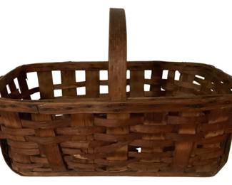 473 - Antique Woven Splint Gathering Basket (Description): Some reeds are split - Antique woven splint gathering basket featuring a single fixed center handle. The rectangular basket displays traditional splint weaving construction with an open lattice pattern along the upper rim. The natural wood has developed a warm brown patina consistent with age and use. Measures 16 inches by 24 inches by 15 inches.