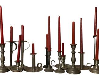 223 - Lot of Assorted Pewter Candleholders (Description): A collection of pewter candleholders in various styles and sizes. The lot includes traditional baluster-form candlesticks, chamberstick holders with finger loops, and taper holders. Several pieces feature classic turned designs while others display simple, utilitarian forms. The candleholders are shown with red taper candles.