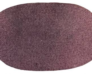 107 - Braided Oval Rug in Plum 29"x18" (Description): Braided oval rug in a deep plum or mauve color. This decorative textile features a traditional coiled braided construction in a solid tone. Measures 29 inches by 18 inches.