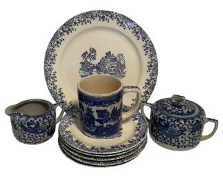 10 - 9pcs Blue & White China - AS IS - Chipped (Description): Nine piece blue and white china set featuring various transferware patterns. The collection includes plates of varying sizes with scenic chinoiserie designs, a mug with blue willow-style decoration, a creamer with phoenix or bird motif, and a covered sugar bowl with scrolling floral pattern. Sold as-is with chips noted.
