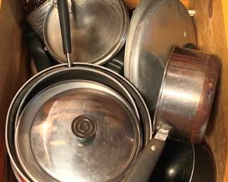 53 - Drawer Lot of Assorted Pots & Pans (Description): A drawer lot of assorted pots and pans including stainless steel cookware, saucepans with lids, a copper-bottom pan, and various cooking vessels with black handles. The collection includes multiple lids and appears to contain both everyday cooking pots and specialty pieces in various sizes.