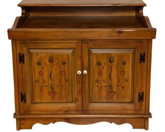 238 - Wood Cabinet / Dry Sink w/ Floral Motif (Description): Wooden cabinet stand featuring decorative painted floral and heart motifs on the front door panels. The piece has a warm honey-toned finish with a raised back splash gallery, two cabinet doors with white porcelain knobs, and black metal strap hinges. The base features a scalloped apron detail. Pennsylvania Dutch or folk art inspired design. Measures 35" x 37" x 22".