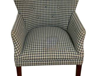457 - Vtg Blue Gingham Upholstered Armchair (Description): Vintage armchair featuring blue and white gingham check upholstery with button-tufted back. The chair has a curved back design with sloped arms and rests on dark wood tapered legs. Measures 35"x28"x30". Stains on seat