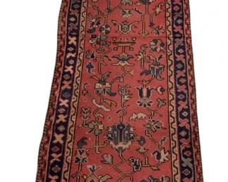 105 - Antique Persian Style Runner Rug 101"x28" (Description): A handsome antique Persian-style runner rug measuring 101 inches by 28 inches. The rug features a rich terracotta red field decorated with traditional stylized floral and geometric motifs in shades of navy blue, cream, and gold. The central field is framed by a classic navy blue border with repeating diamond and X-pattern designs. The rug displays characteristic hand-knotted construction with natural fringe at both ends
