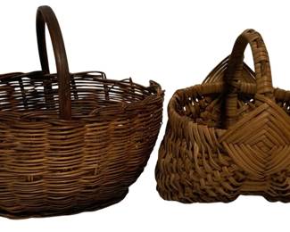 73 - 2 Antique Woven Wicker Baskets 6"x6"x5" (Description): Two antique woven baskets. The collection includes a round wicker gathering basket with a tall bentwood handle and an egg basket style piece featuring a distinctive diamond-pattern woven center divider and looped handle. Both baskets display rich brown patina consistent with age. Measurements: 6" x 6" x 5".