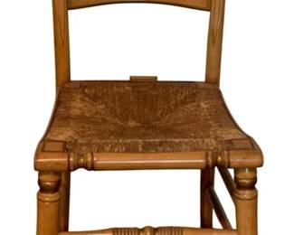 145 - Painted Wood Chair 33.5"x17"x16" (Description): A painted wood chair featuring decorative floral motifs on the back splat and crest rail. The chair has a woven rush seat (worn) and turned legs with stretchers. Measures 33.5 inches high by 17 inches wide by 16 inches deep.