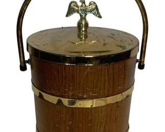 23 - Vtg Wood Ice Bucket w/ Brass Eagle Finial (Description): Vintage ice bucket featuring a wooden barrel-style body with brass banding and trim. The lid is topped with a decorative brass eagle finial, and the bucket has a curved brass handle and rests on ball feet. A handsome mid-century barware piece with patriotic styling. Measures 11" x 8".