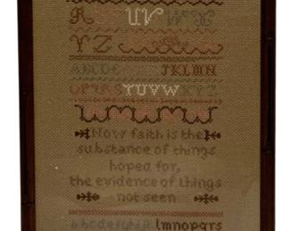 62 - Framed Needlepoint Sampler 16"x8.5" (Description): Framed needlepoint sampler featuring multiple alphabet rows worked in various decorative stitches and colors including red, green, brown, and gold tones. The sampler includes a religious verse reading "Now faith is the substance of things hoped for, the evidence of things not seen." Finished with initials "SAH" and the date 1989 at the bottom, along with decorative crown and floral motifs. Presented in a dark wood frame with
