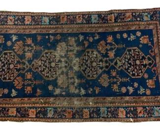 104 - Antique Persian Style Wool Rug 53"x32" (Description): Antique Persian style wool rug featuring a deep blue field with four central medallions decorated with stylized floral and geometric motifs. The design includes small animal and plant figures scattered throughout the field. The border displays a complementary pattern with coral, rust, and blue tones against a darker ground. The rug shows age-appropriate wear with some fading and pile loss to the central area, and fringe visible at the ends.