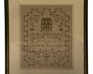 61 - Framed Needlepoint Sampler w/ House (Description): Framed needlepoint sampler featuring a central house motif surrounded by decorative vine borders. The piece includes a cross-stitched alphabet and numerals in a traditional style, with floral and geometric elements throughout. Worked in muted green thread on a light linen ground, the sampler is professionally matted and presented in a green and gold frame. Measures 16" x 12.5".