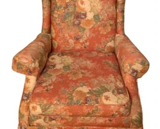 235 - Floral Upholstered Wingback Chair 46"x30"x29" (Description): A traditional wingback chair upholstered in a coral-toned floral fabric featuring roses and foliage in shades of cream, yellow, green, and burgundy. The chair features rolled arms, a high back with curved wings, and a skirted base. Measures 46 inches high by 30 inches wide by 29 inches deep.