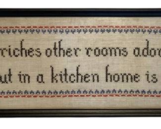 25 - Framed Kitchen Motto Cross Stitch 7.5"x20.5" (Description): Framed needlepoint cross stitch sampler featuring the motto "Life's riches other rooms adorn but in a kitchen home is born." Presented in a black wooden frame. Measures 7.5" x 20.5".