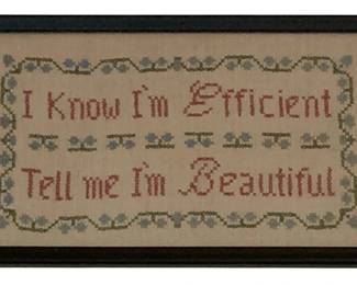 5 - Framed Needlepoint Sampler 8"x13.25" (Description): Framed needlepoint sampler featuring the phrase "I Know I'm Efficient Tell Me I'm Beautiful" stitched in red lettering on a cream background. The piece is decorated with a border of blue flowers and green vines. Presented in a dark wooden frame. Measures 8" x 13.25".